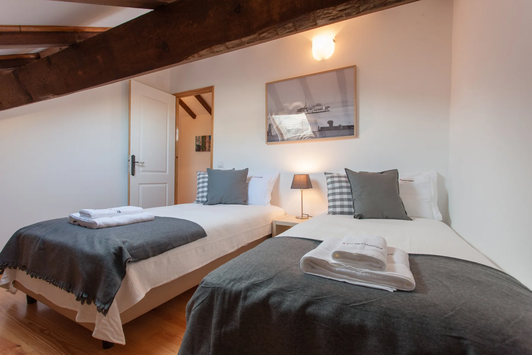 A bedroom with two beds, folded towels, and a framed picture on the wall.