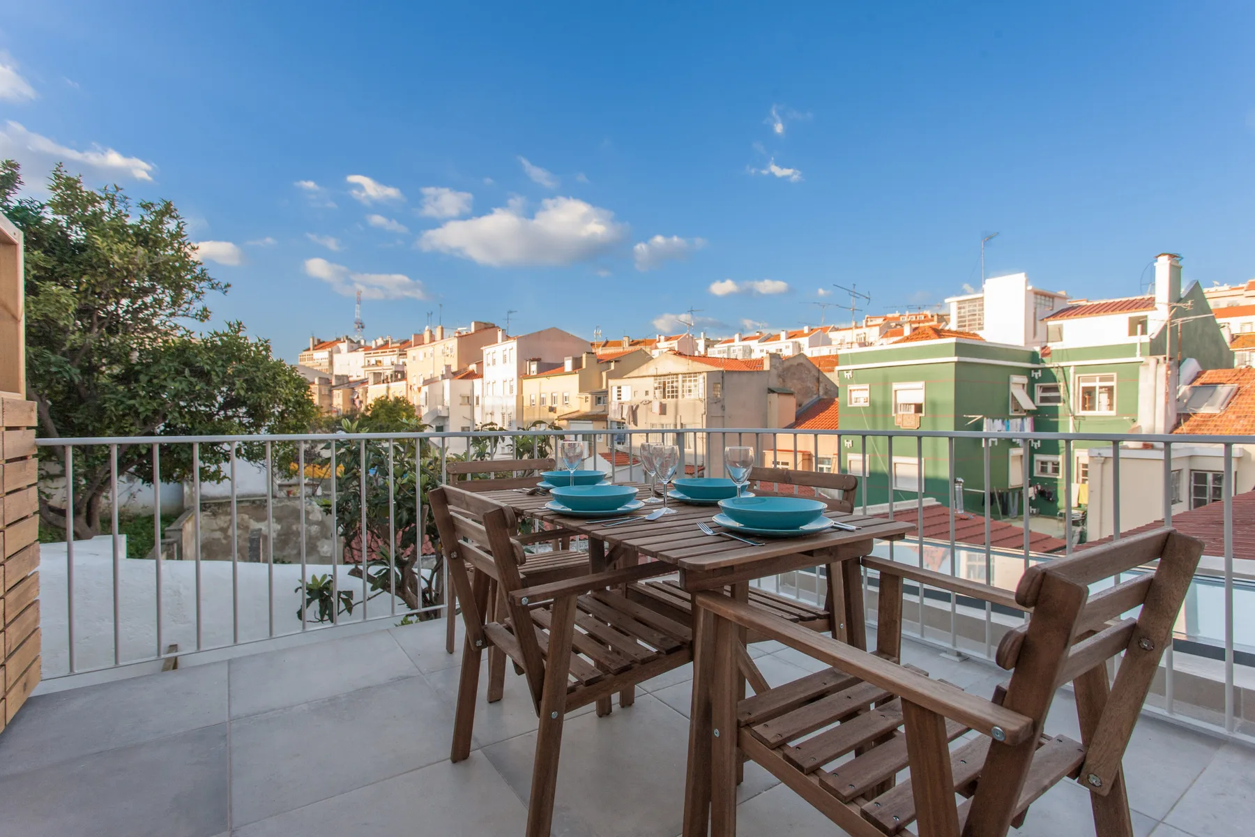 A rooftop terrace with outdoor seating and a table overlooking nearby buildings.