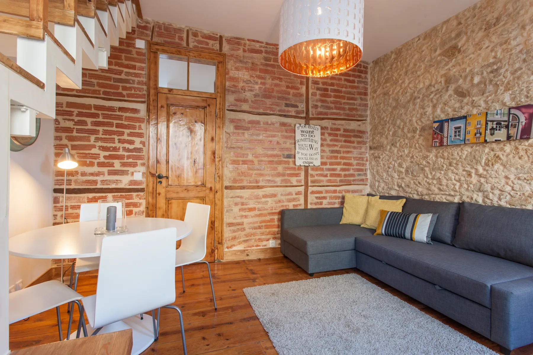 A living and dining area with a gray sectional sofa beside a white table.