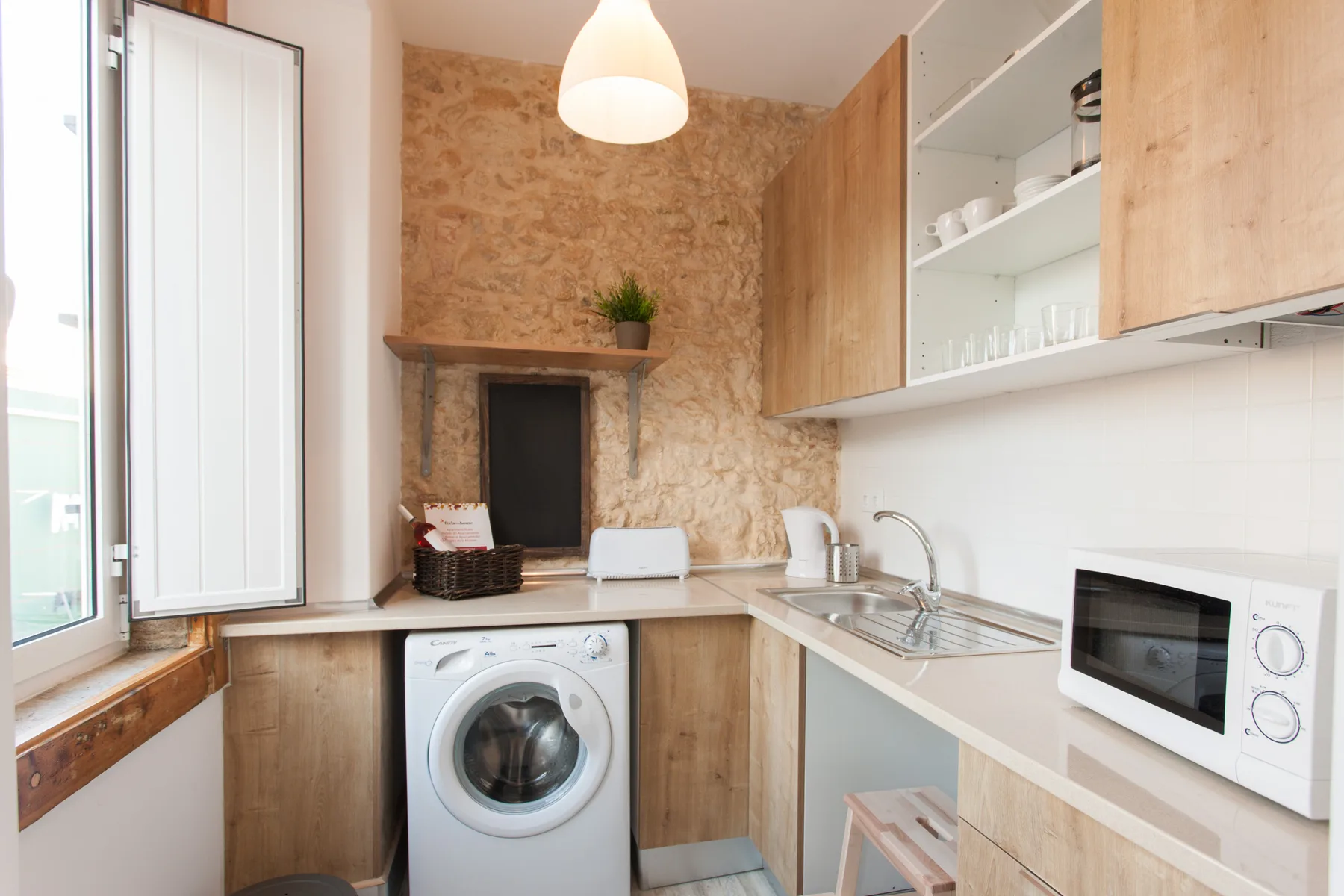 A compact kitchen with a sink, washing machine, and microwave.