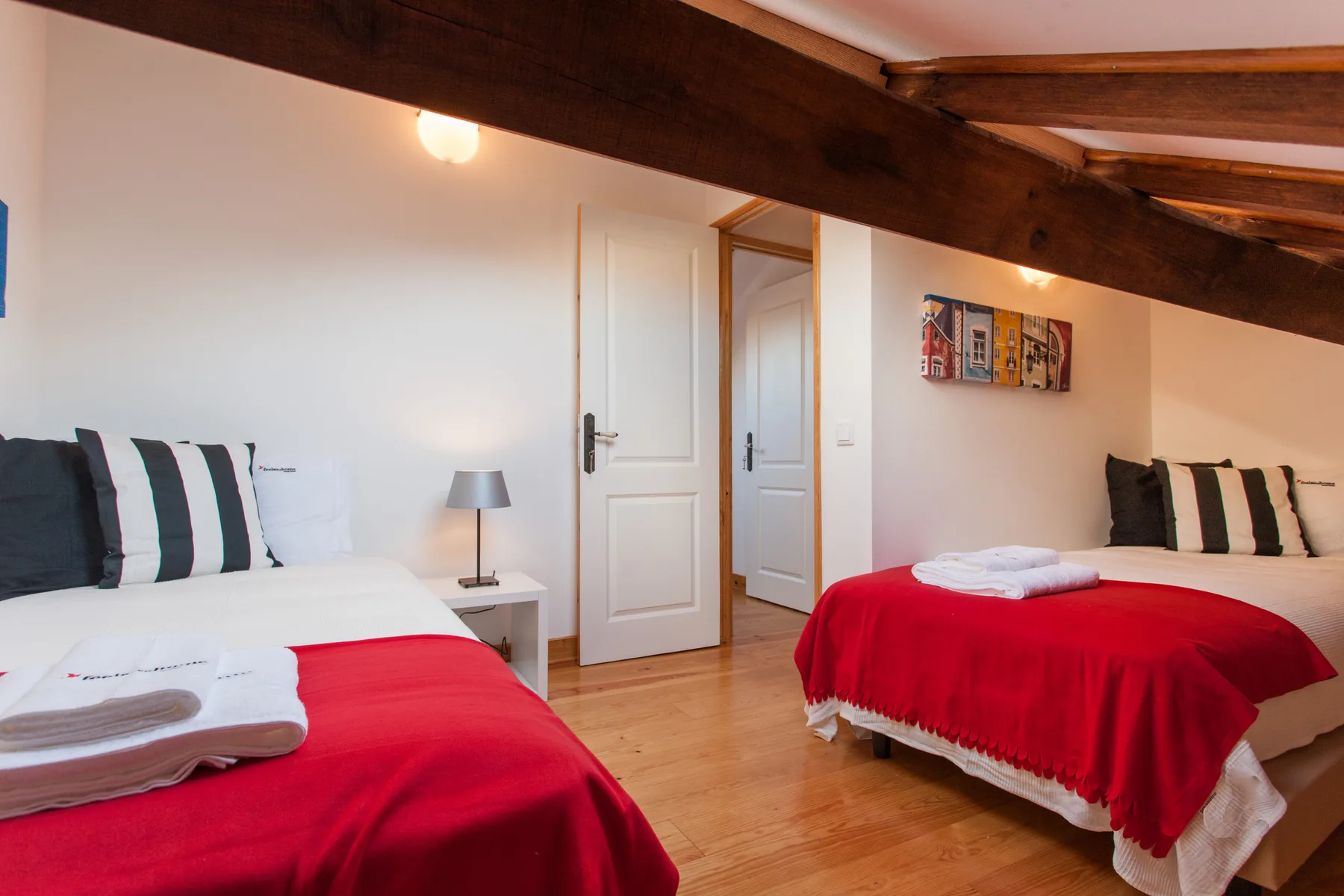 A bedroom with two beds dressed in red and white linens.