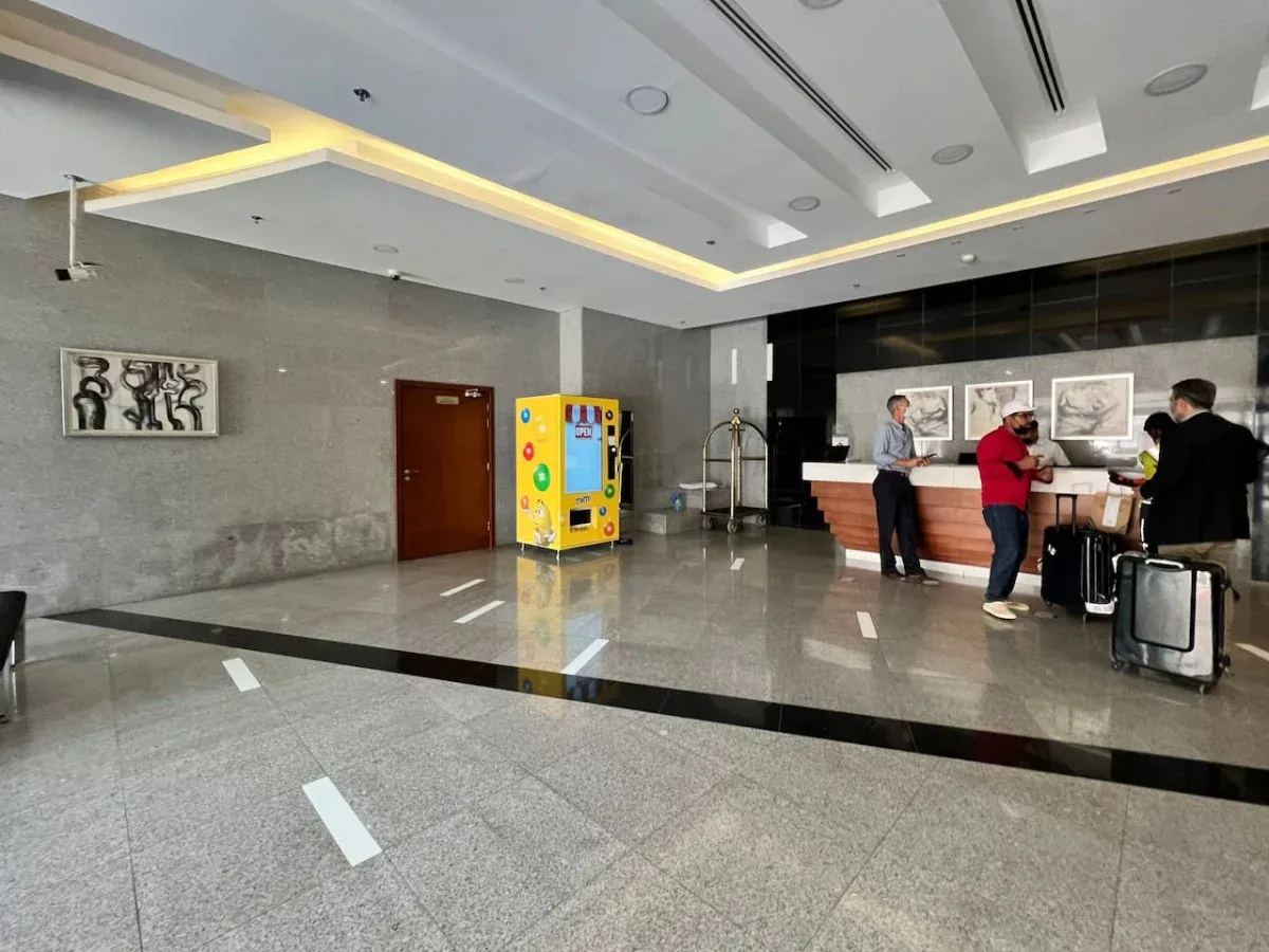 A modern lobby with a reception desk, vending machine, and polished stone floor.