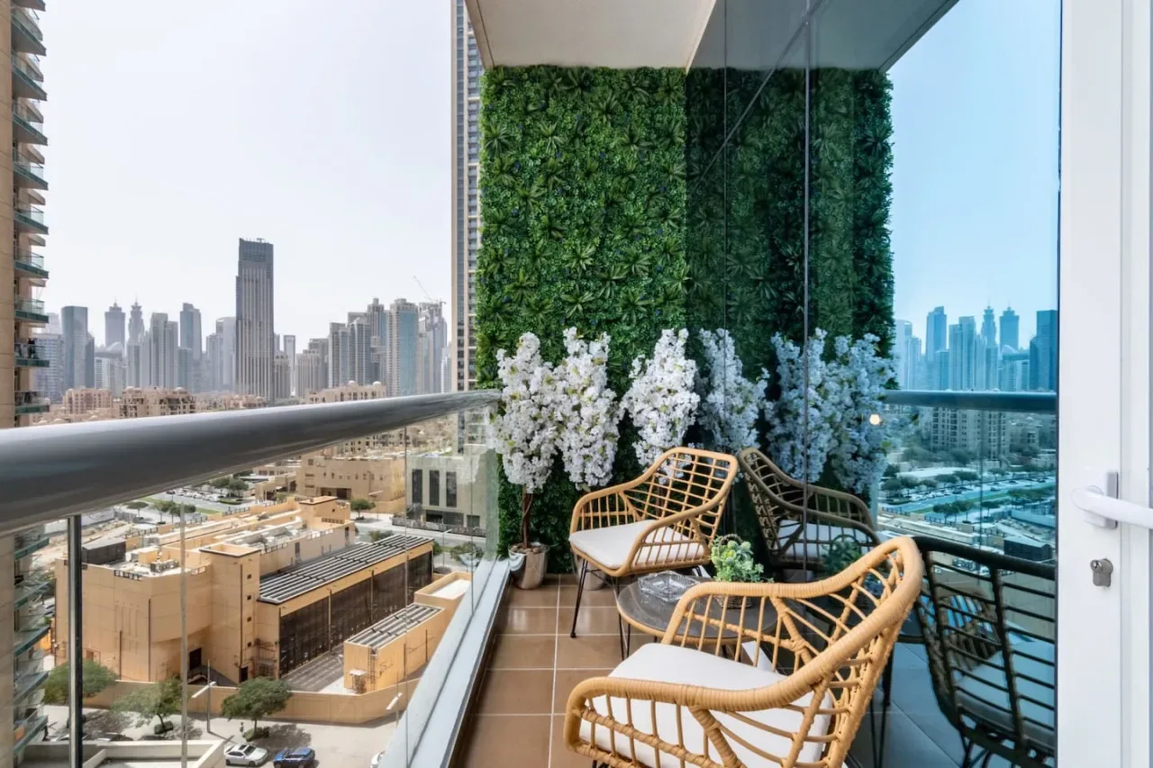 A glass balcony with wicker seating overlooks the city skyline.