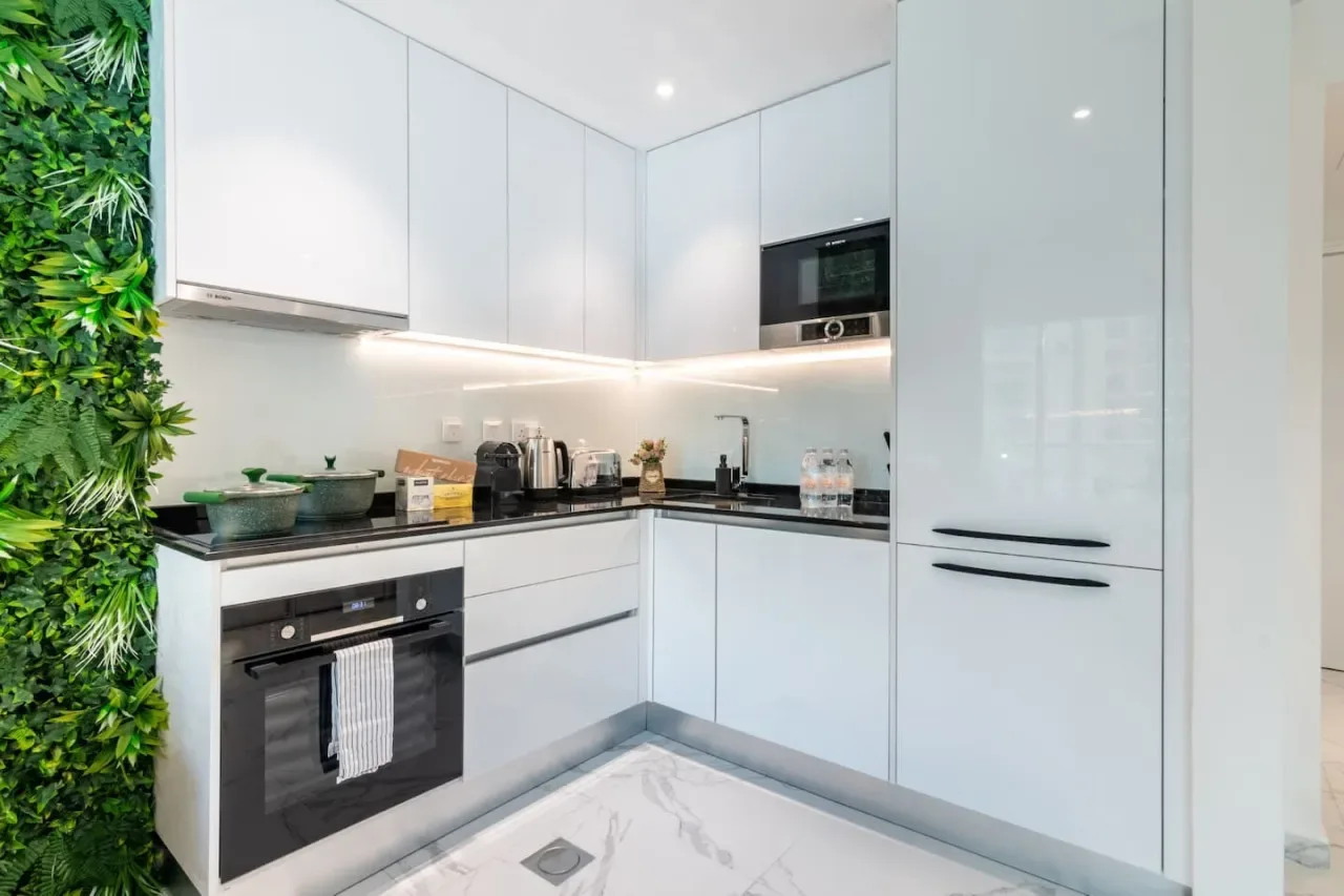 A modern kitchen with white cabinetry, dark countertops, and built-in appliances.