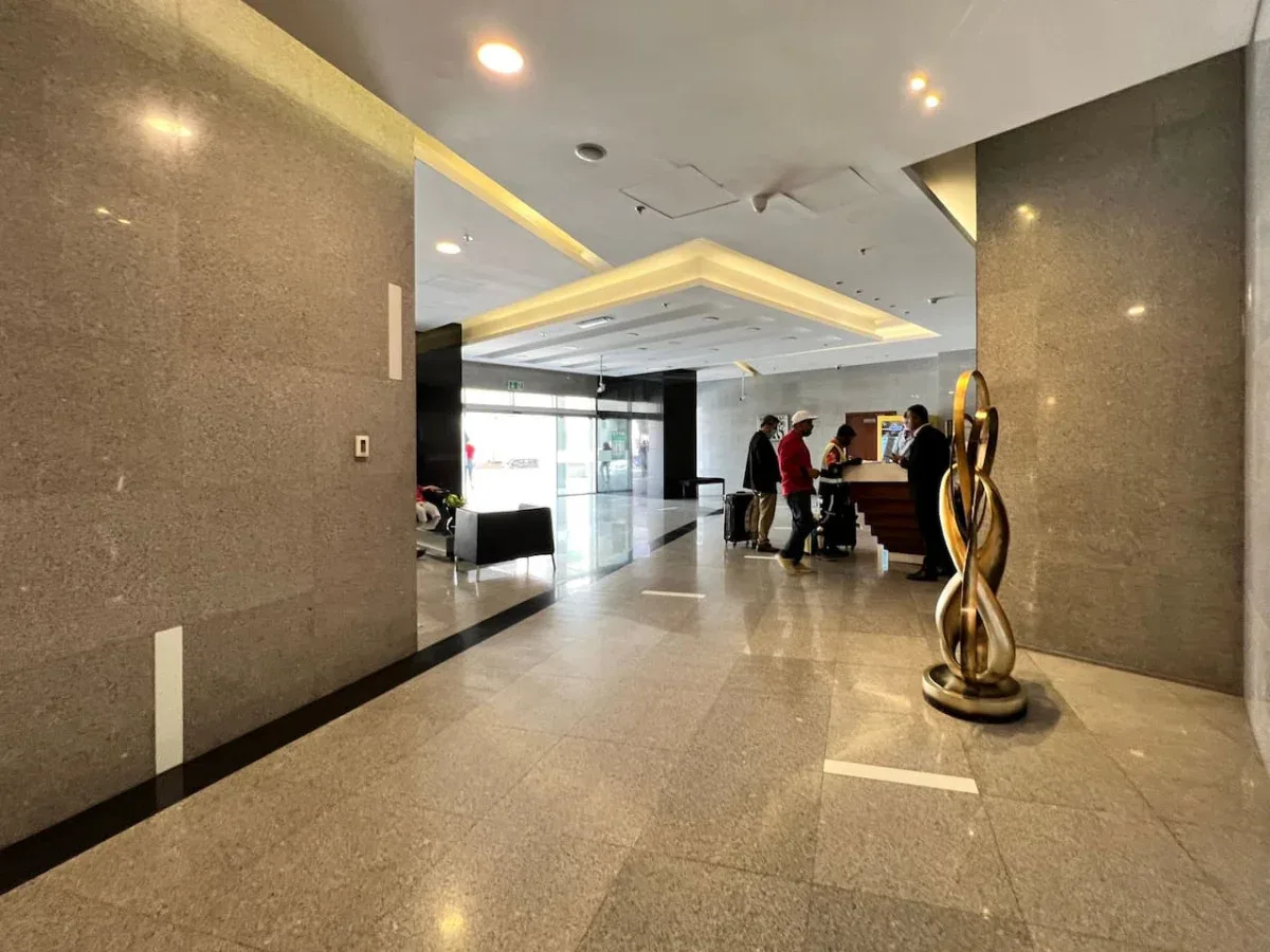 A hotel lobby with a reception desk and a decorative sculpture.