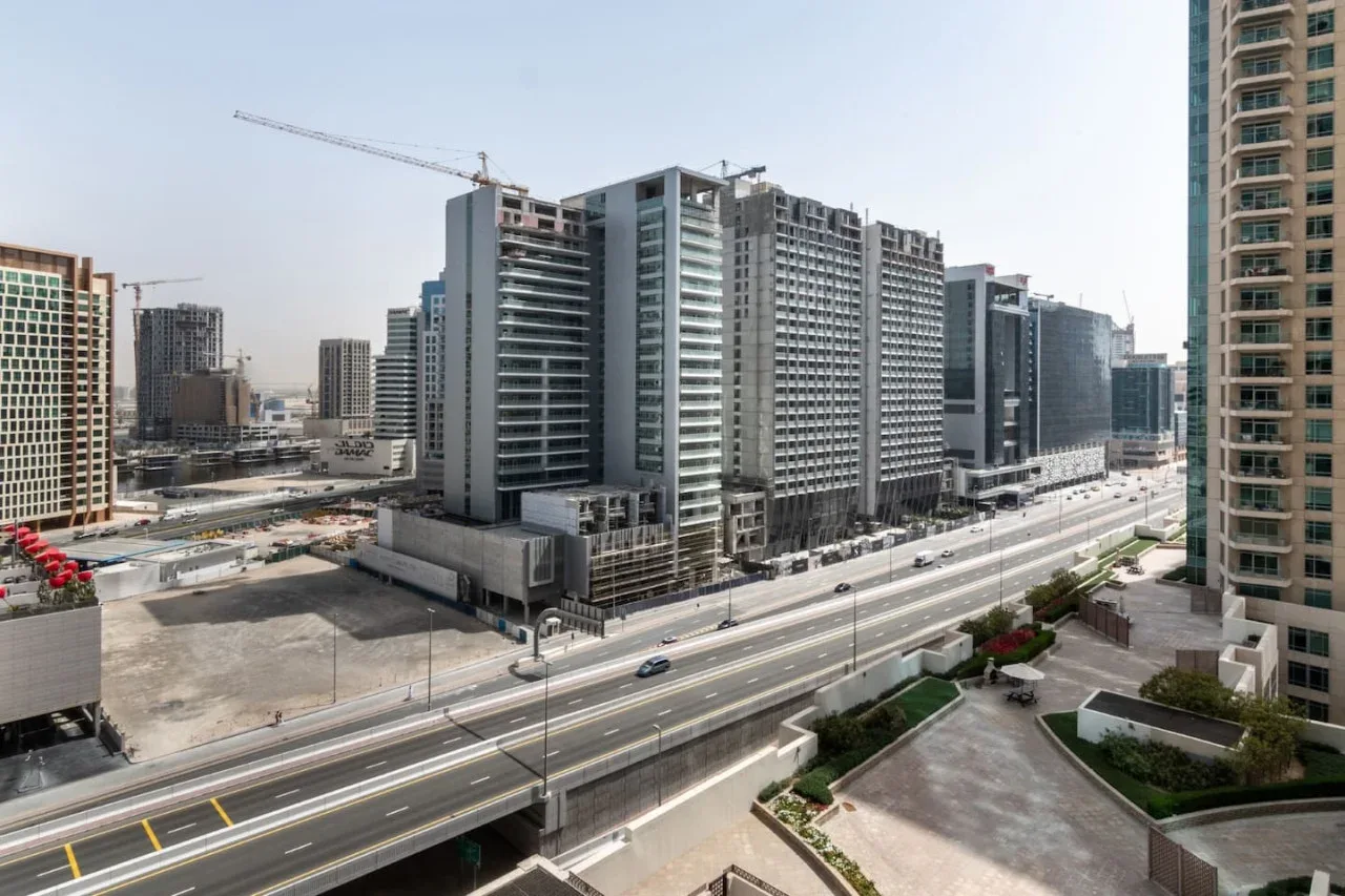 A cityscape of high-rise buildings beside a wide multi-lane road.