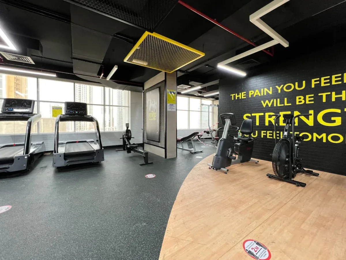 A gym with cardio machines, exercise bikes, and a large motivational wall graphic.