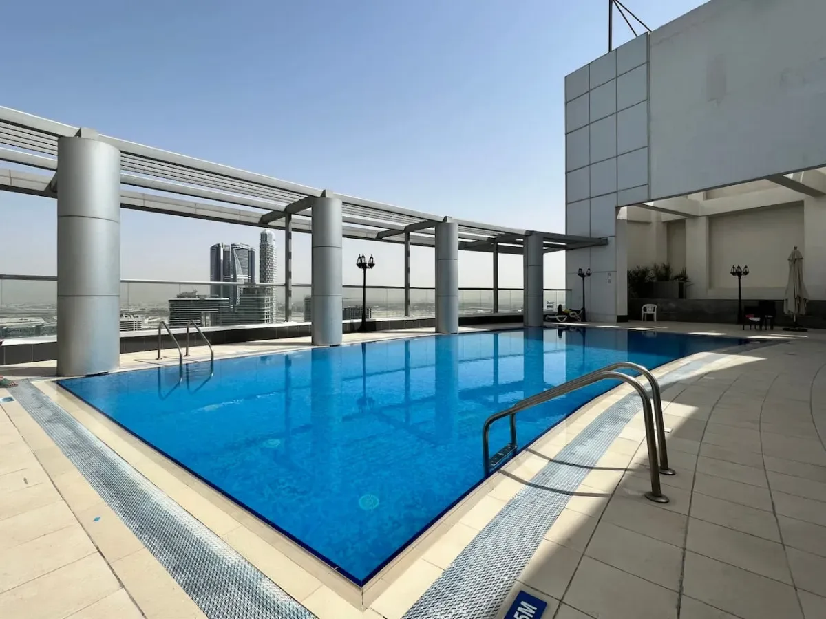 A rooftop swimming pool sits beside a covered terrace with open views of the city.