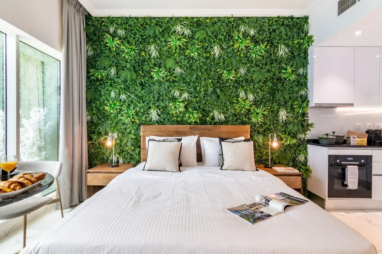 A bedroom with a large bed set against a leafy green wall.