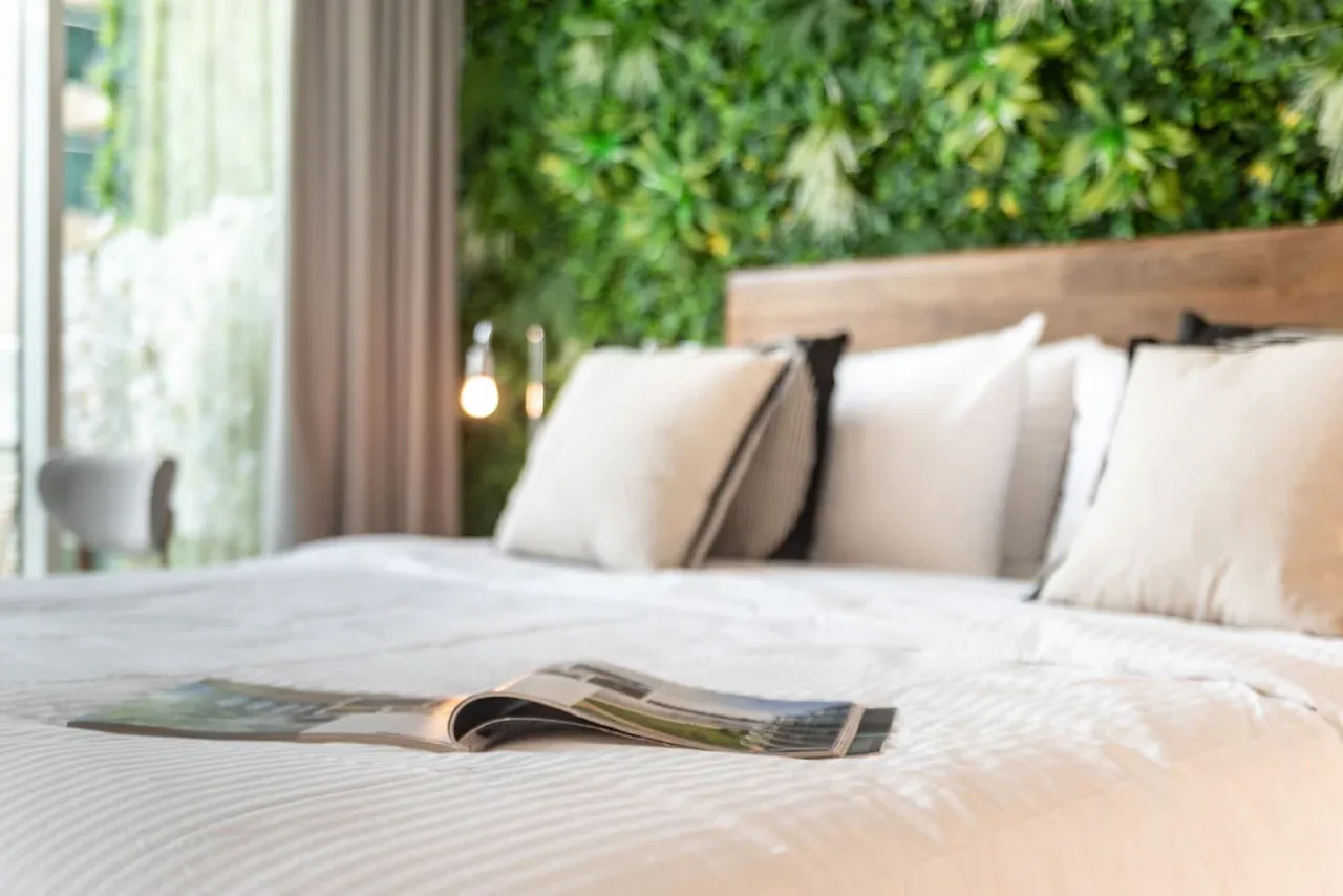 A bedroom with a neatly made bed and an open magazine.