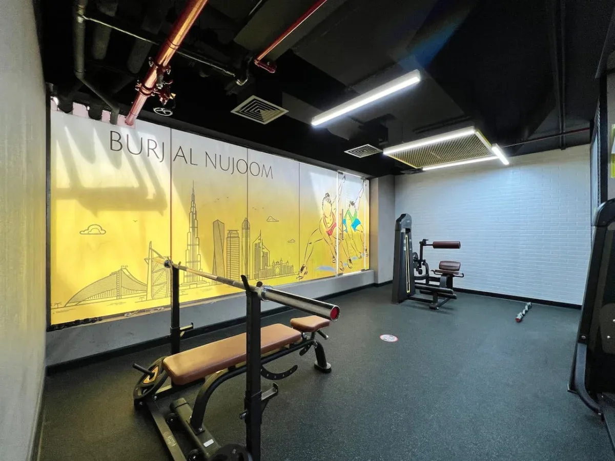 A gym with weight-training equipment and a yellow illustrated wall mural.