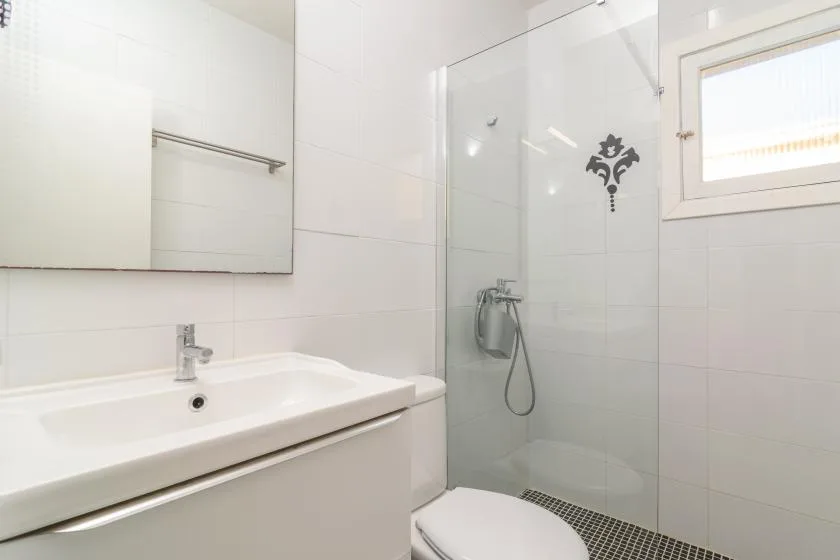 A bright bathroom with a sink and glass shower.