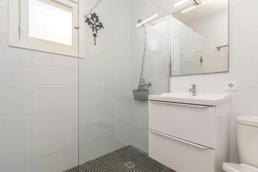 A bright bathroom with a glass shower, sink, and wall mirror.