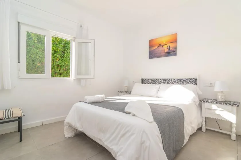 A bright bedroom with a neatly made bed and an open window.