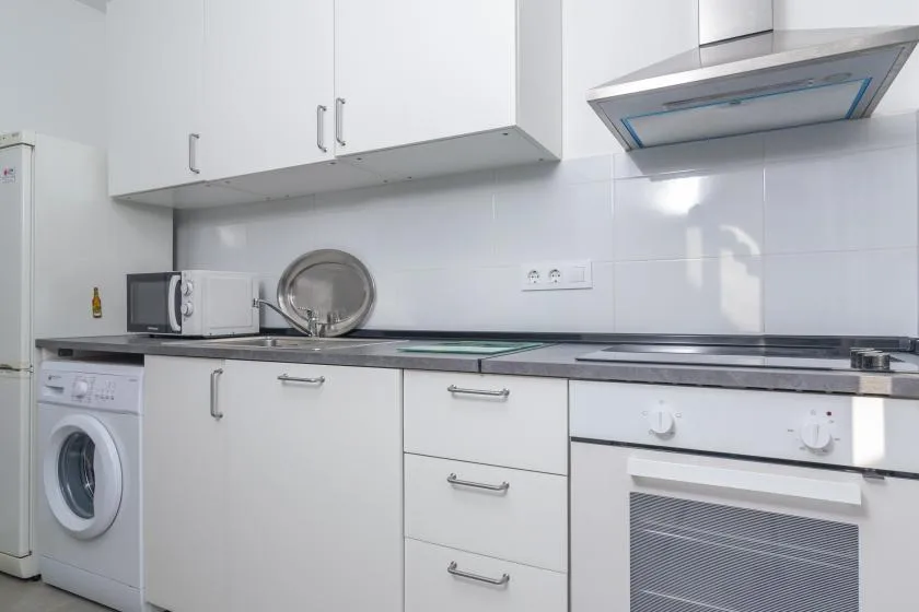 A bright kitchen with white cabinets and a built-in oven.
