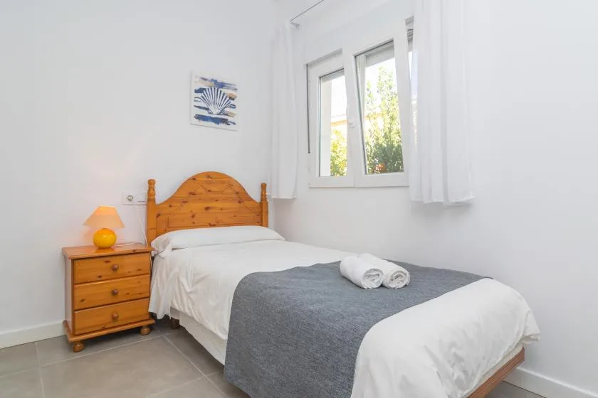 A bright bedroom with a bed dressed in white and gray bedding.