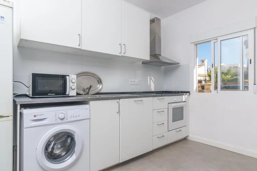 A bright kitchen with white cabinets, a countertop, and a window.
