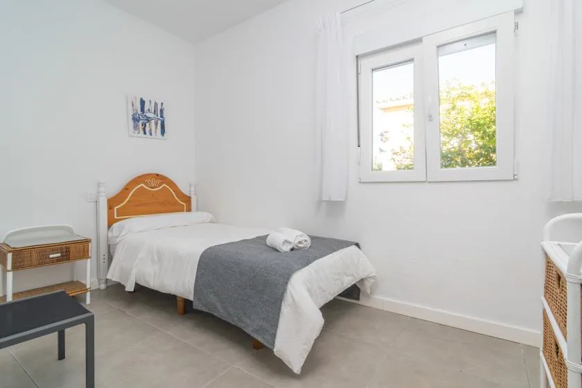 A bright bedroom with a single bed beneath a window.