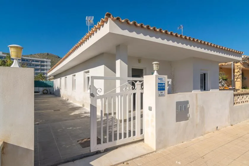 A white building entrance with a metal gate and tiled roof.