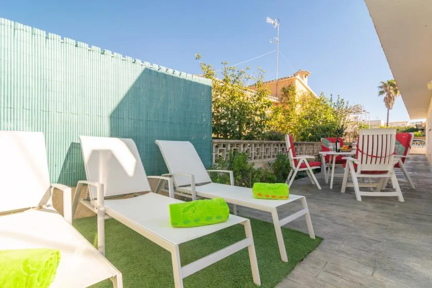 An outdoor patio with lounge seating, a dining table, and green planters.