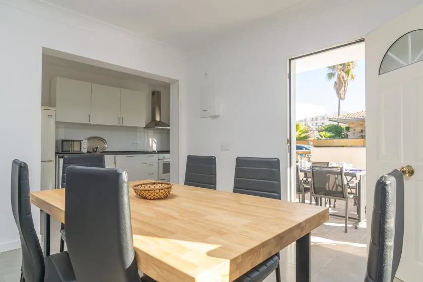 A dining area with a wooden table and an open kitchen behind it.