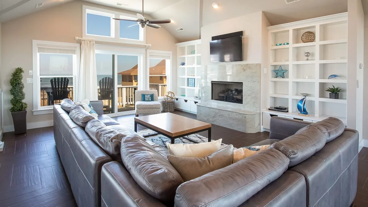 A living room with a sectional sofa, fireplace, and built-in shelving.
