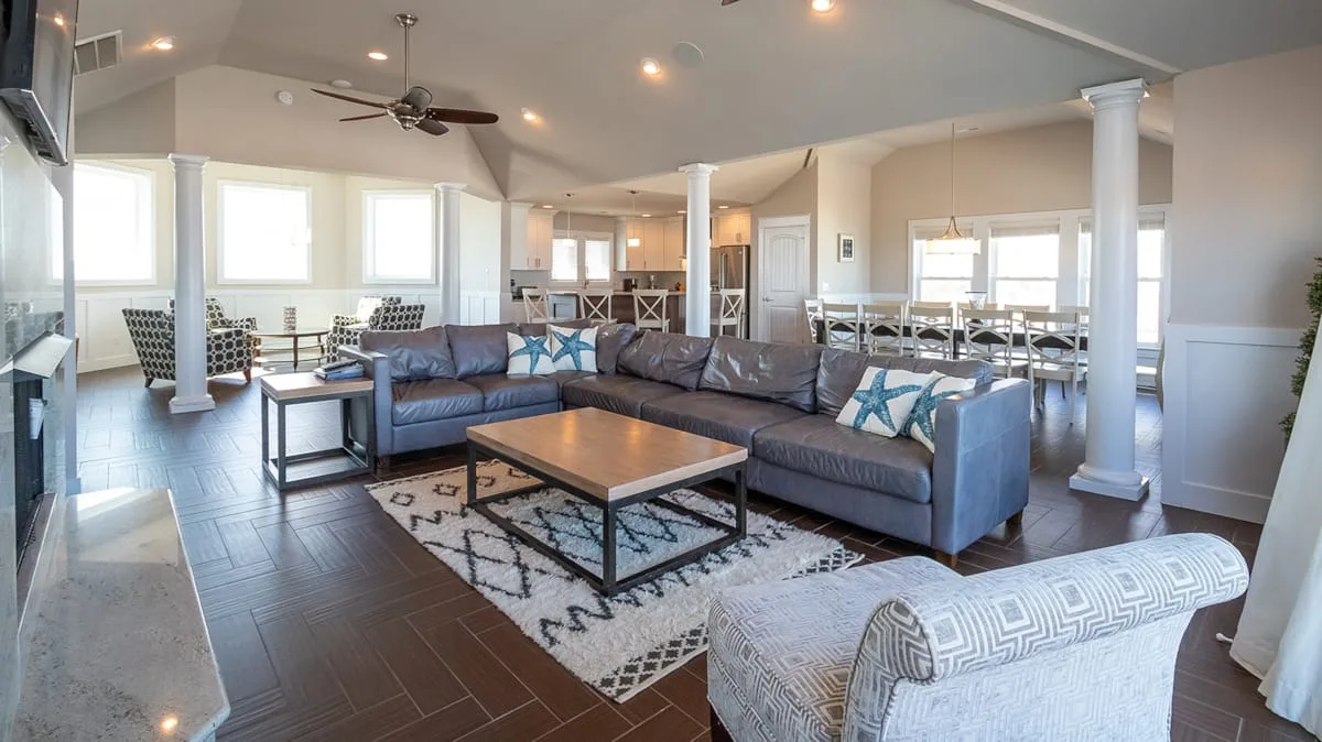 A spacious living room with sectional seating, a coffee table, and a ceiling fan.