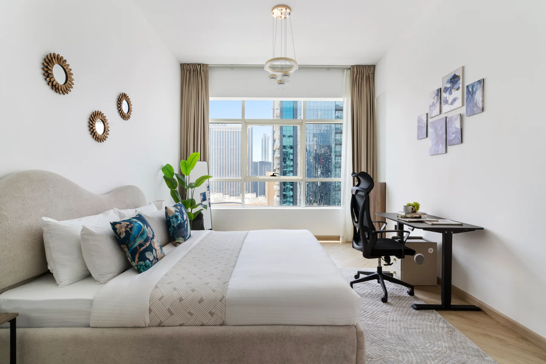 Un dormitorio luminoso con una cama junto a un escritorio y una ventana grande.