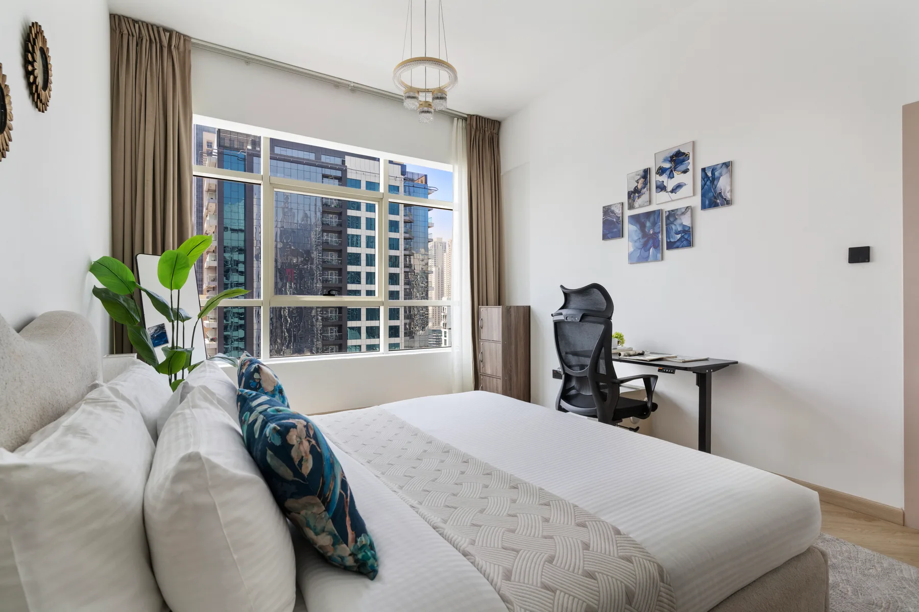 Un dormitorio luminoso con una cama, un escritorio y una gran ventana con cortinas.