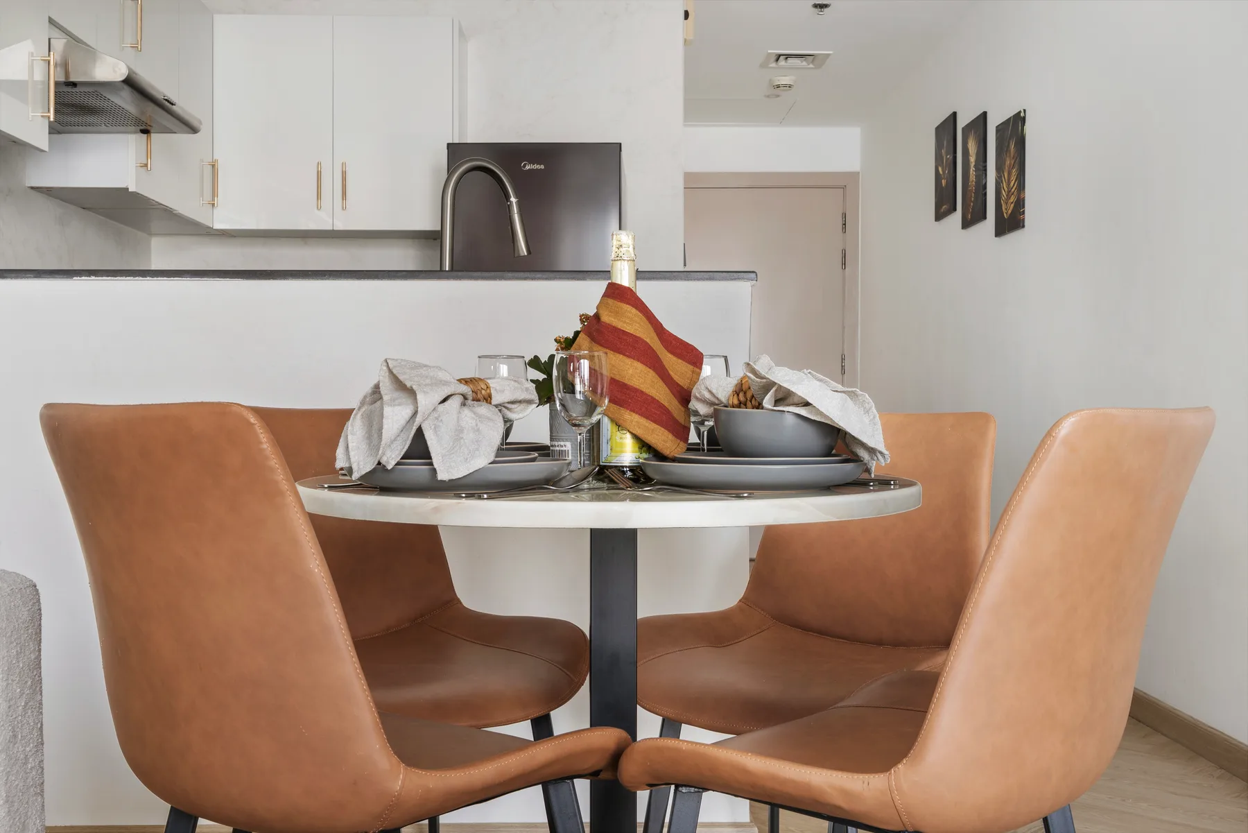 Una mesa de comedor con platos puestos está frente a una cocina compacta.