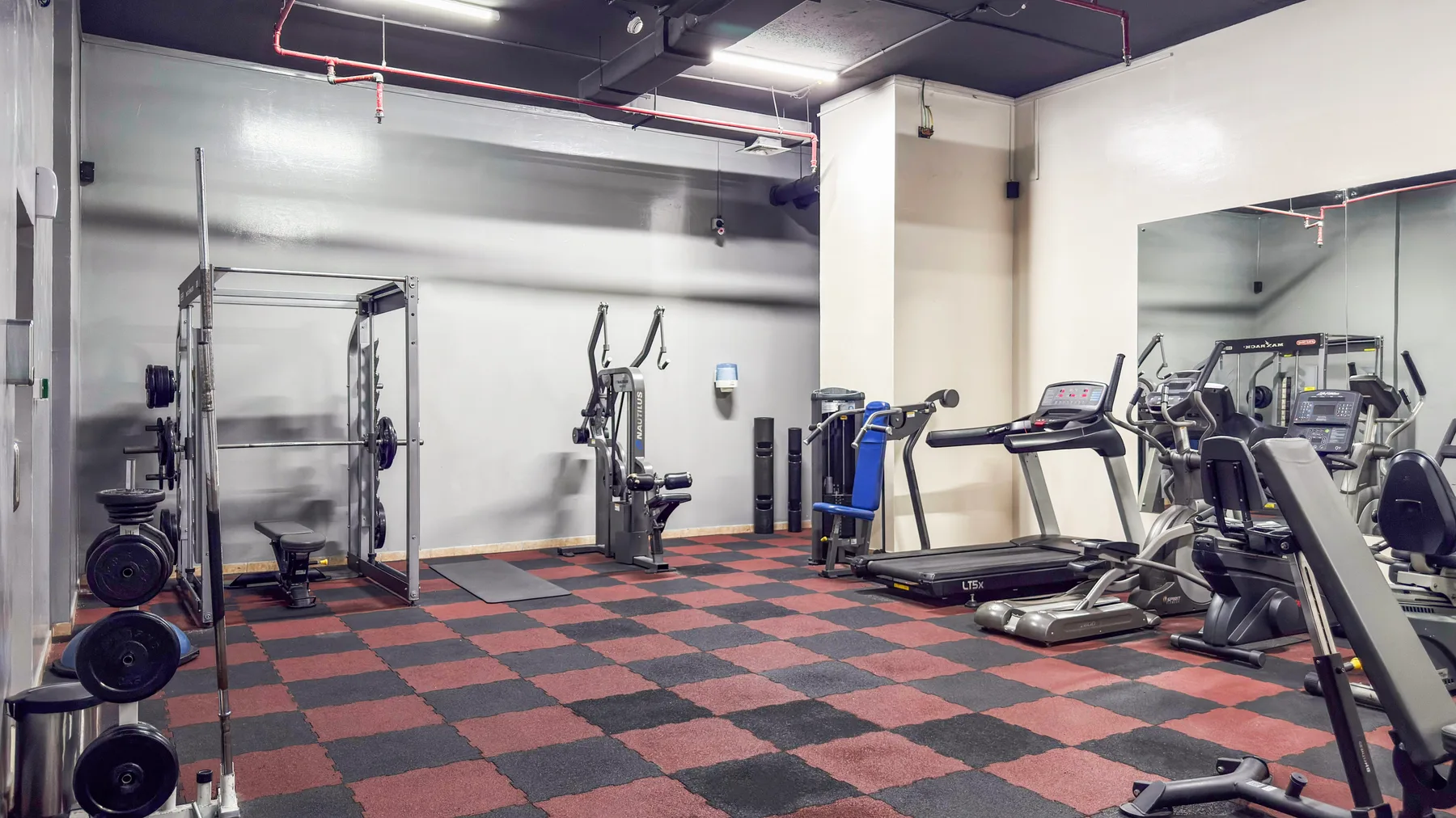Un gimnasio con máquinas de ejercicio y equipo para entrenar con pesas.
