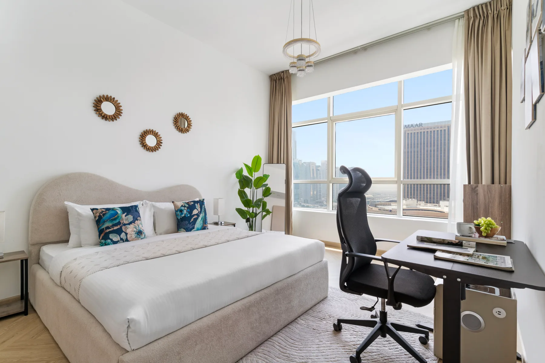 Un dormitorio luminoso con una cama y un escritorio junto a grandes ventanas.