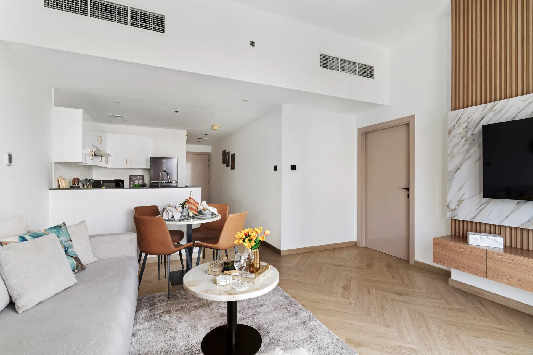 Una luminosa sala de estar y comedor con cocina y televisor.