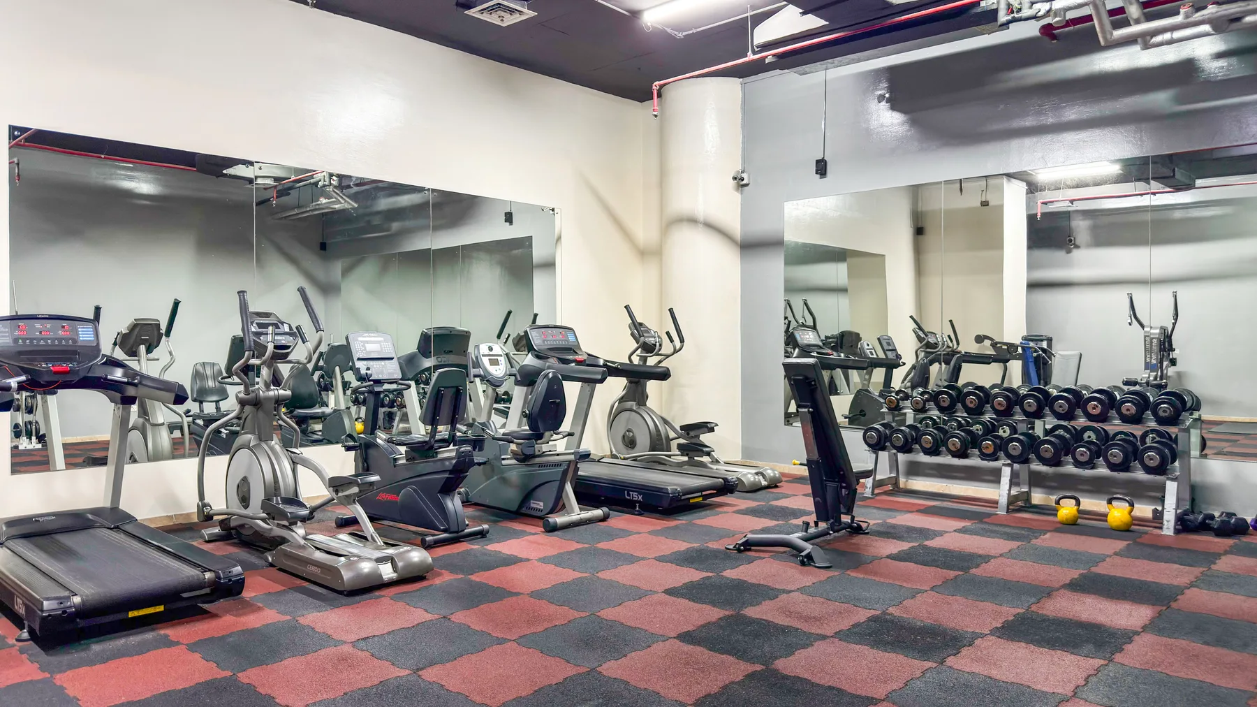 Un gimnasio con máquinas de ejercicio, pesas y suelo de goma.