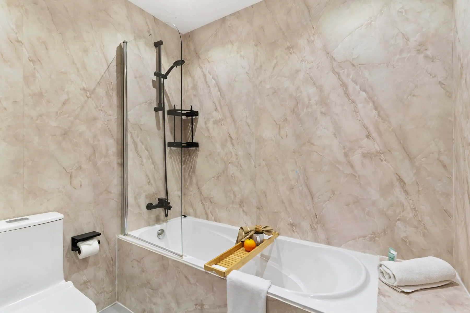 Un baño con bañera, ducha y paredes con patrón de mármol.