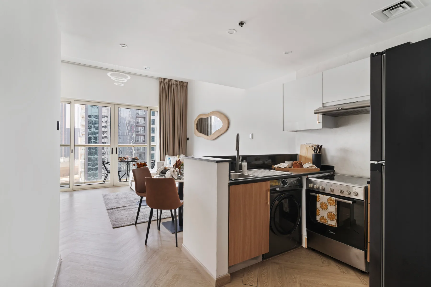 Una cocina y comedor de planta abierta tiene una mesa junto a puertas de vidrio.