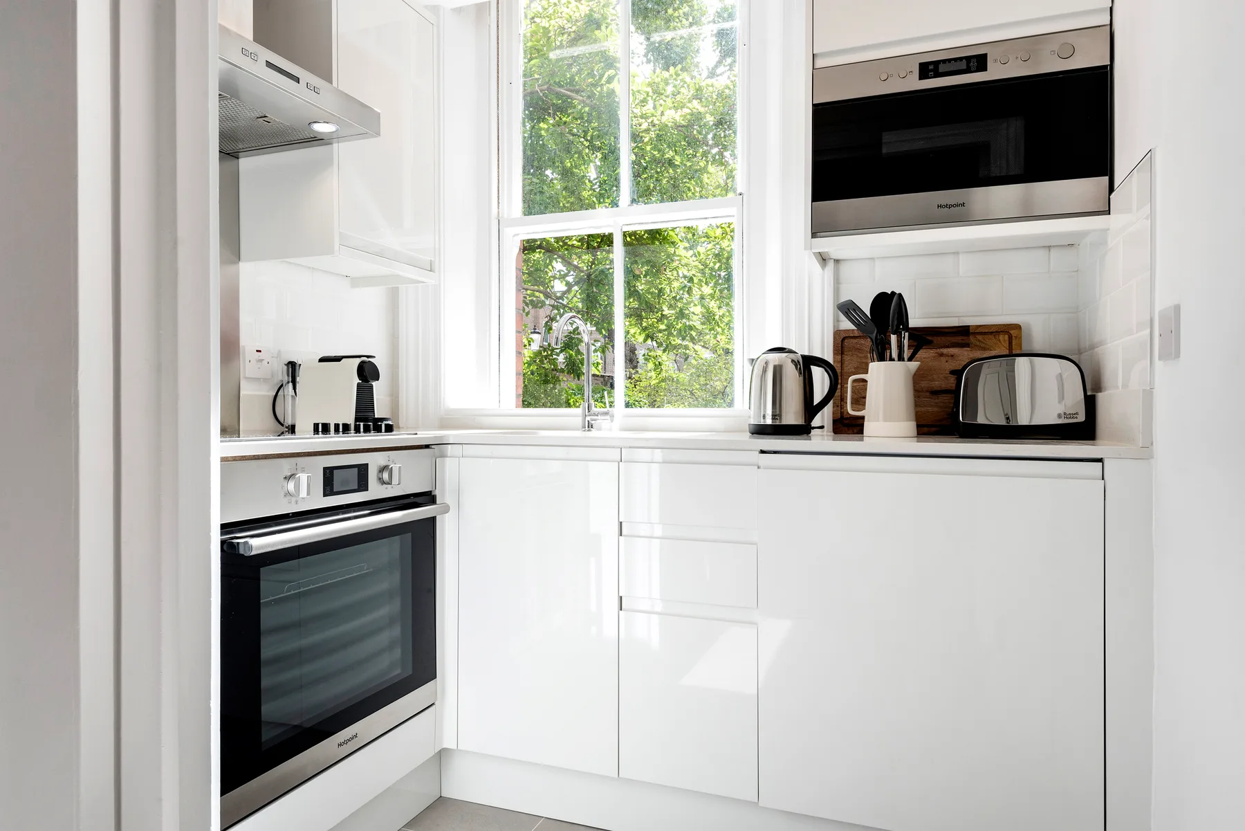 Una cocina blanca y luminosa con una ventana grande sobre la encimera.