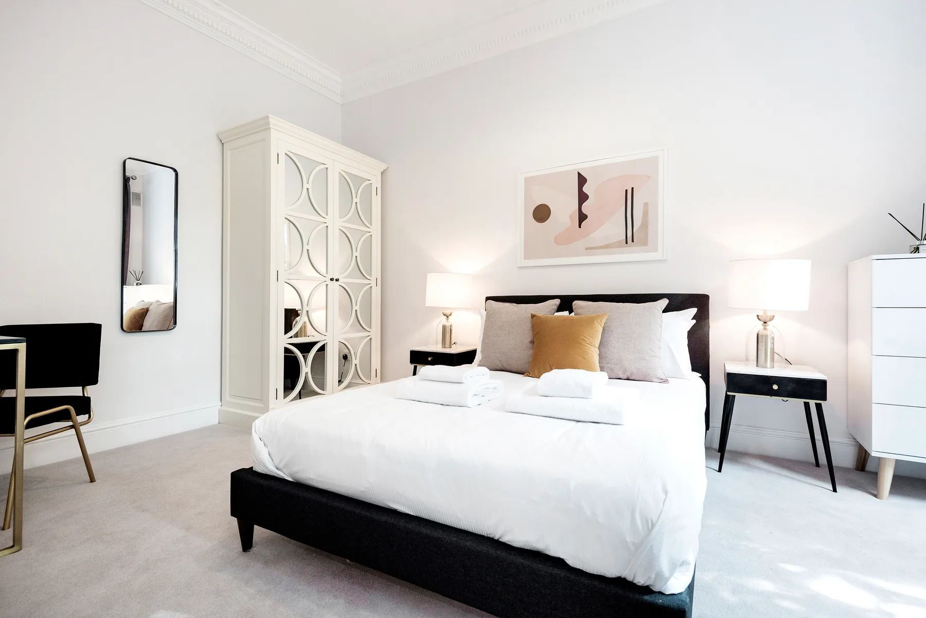 Un dormitorio luminoso con una cama grande y un cuadro encima.