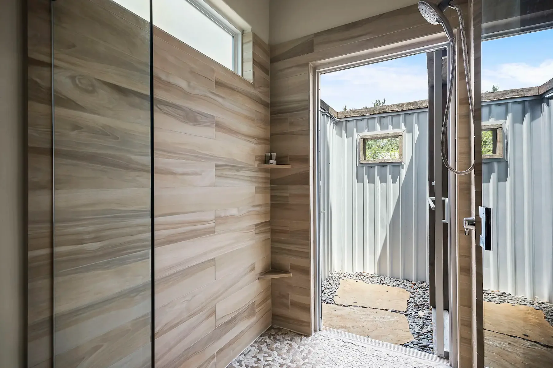 Una zona de ducha con azulejos se abre a un pequeño espacio exterior.