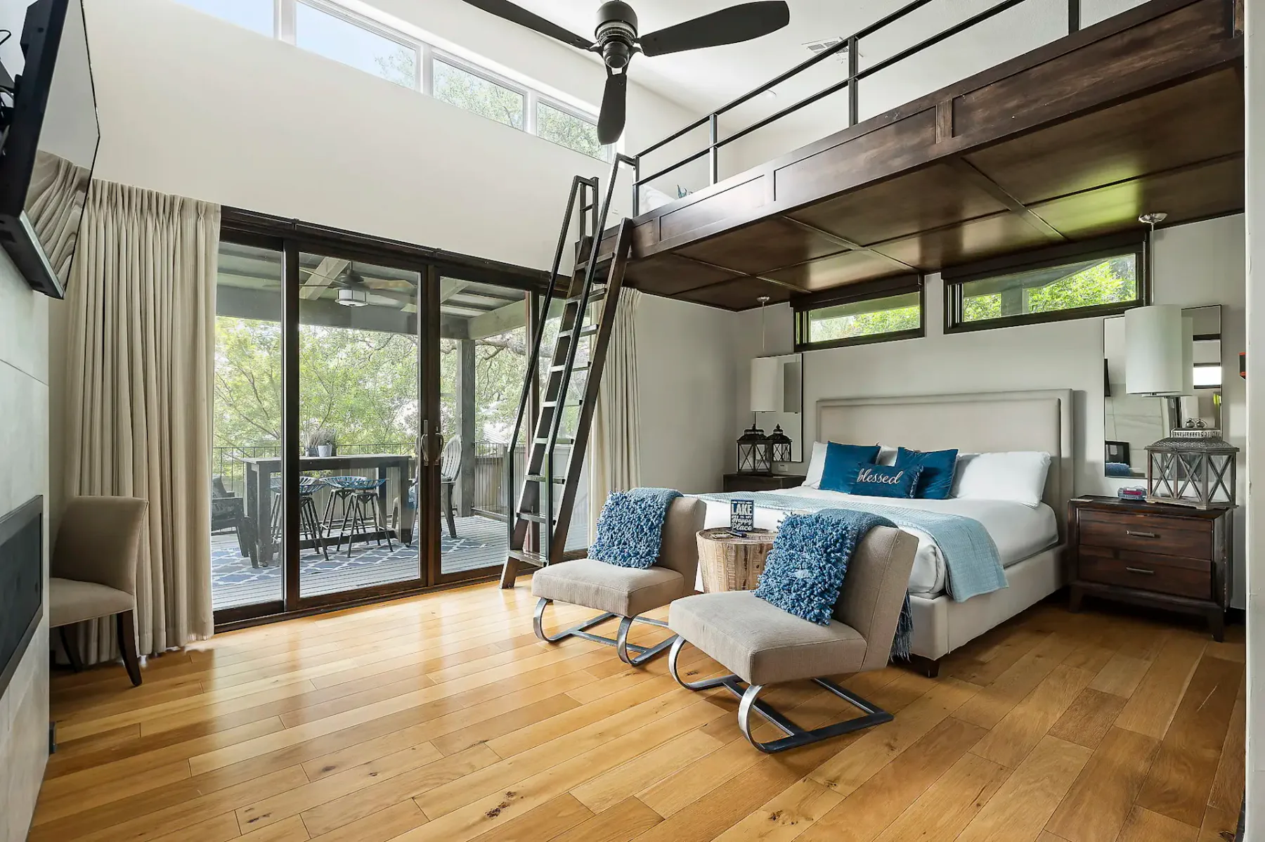 A bedroom with a loft platform, a bed, and sliding glass doors opening onto a deck.