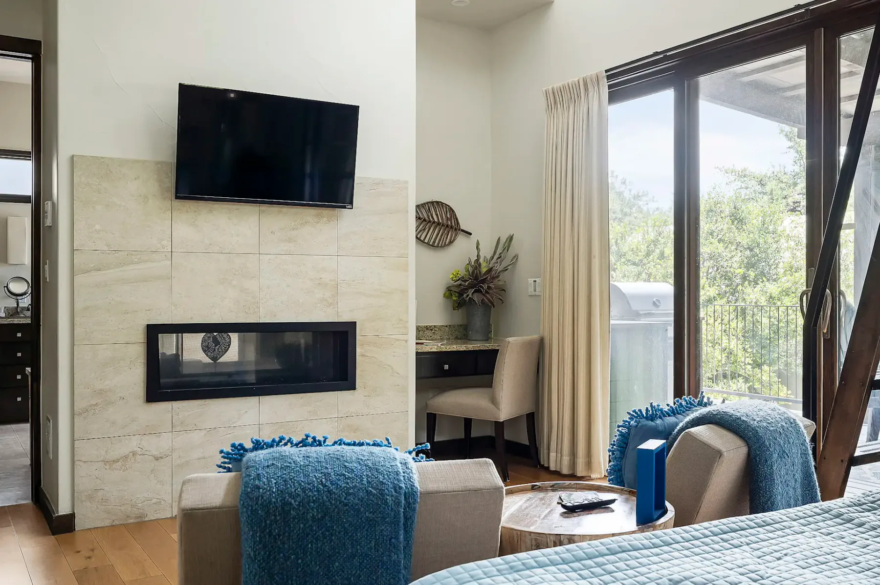 Bedroom with a television above a fireplace and glass doors opening onto a balcony.