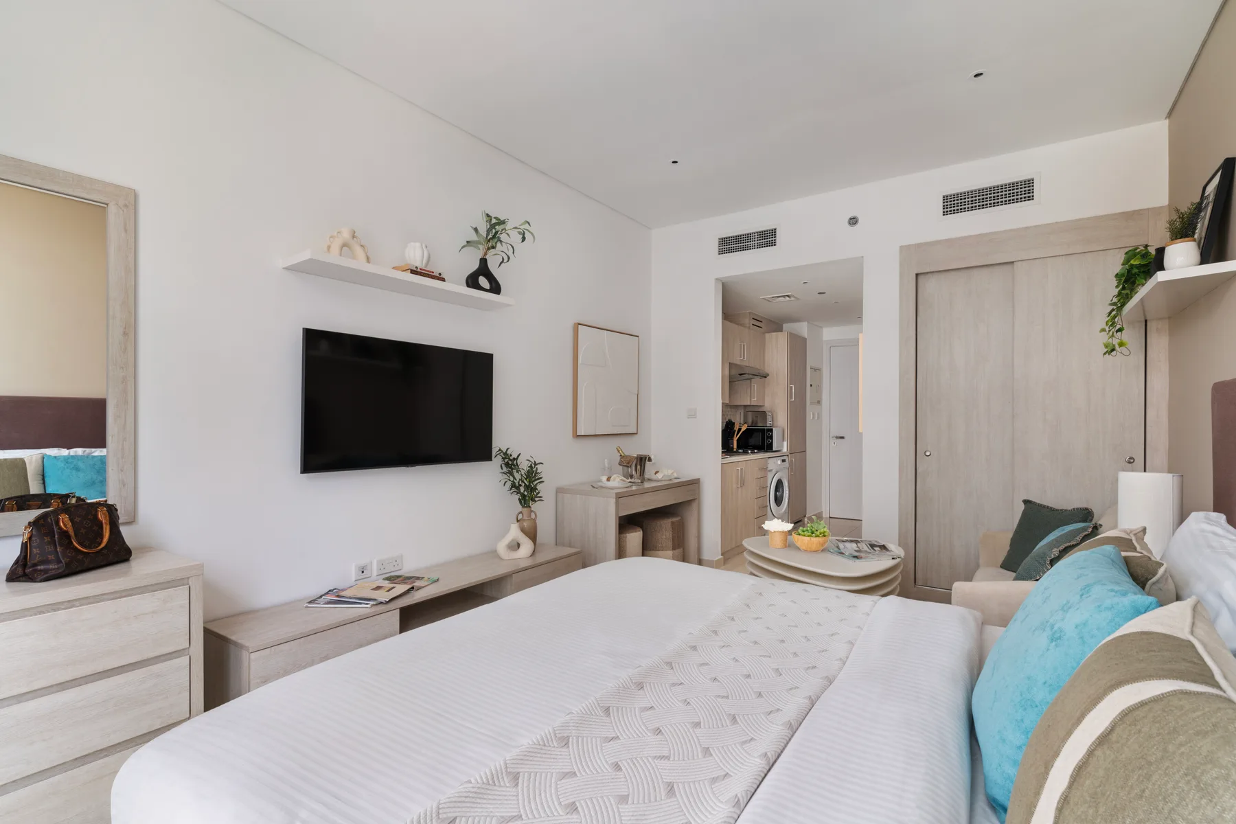 Un dormitorio con una cama, un televisor montado en la pared y una puerta hacia el espacio contiguo.