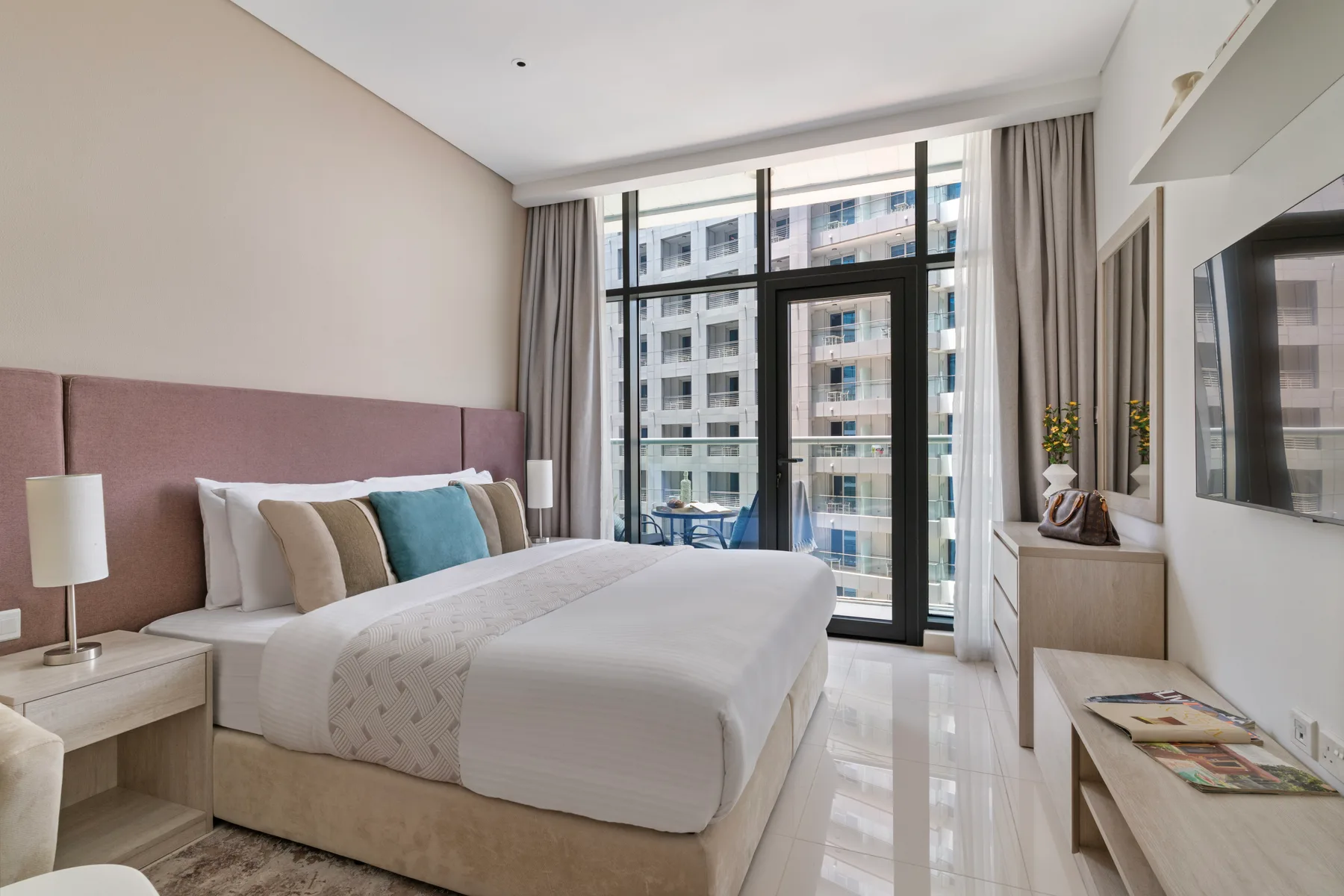 Un dormitorio luminoso con una cama grande junto a ventanas de piso a techo.