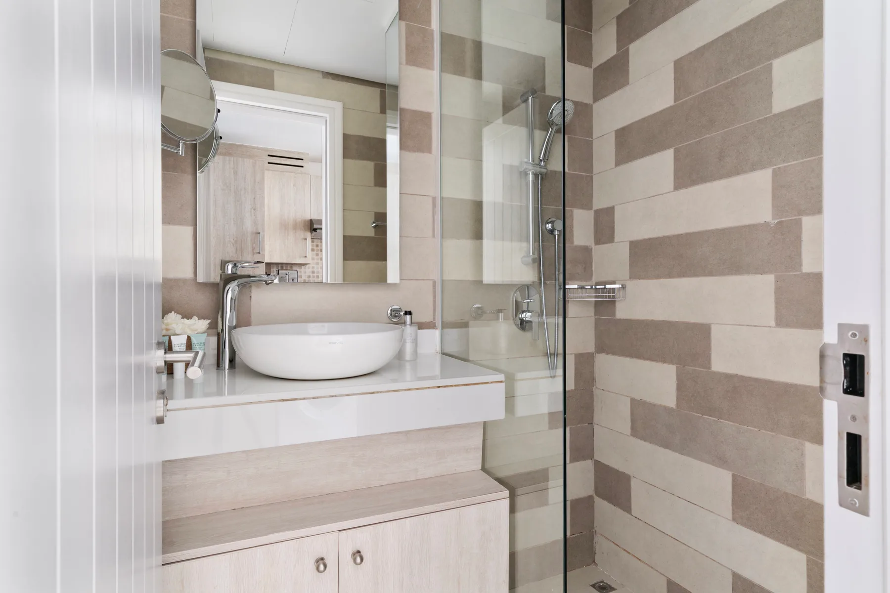 Un lavabo de baño junto a una ducha con azulejos.