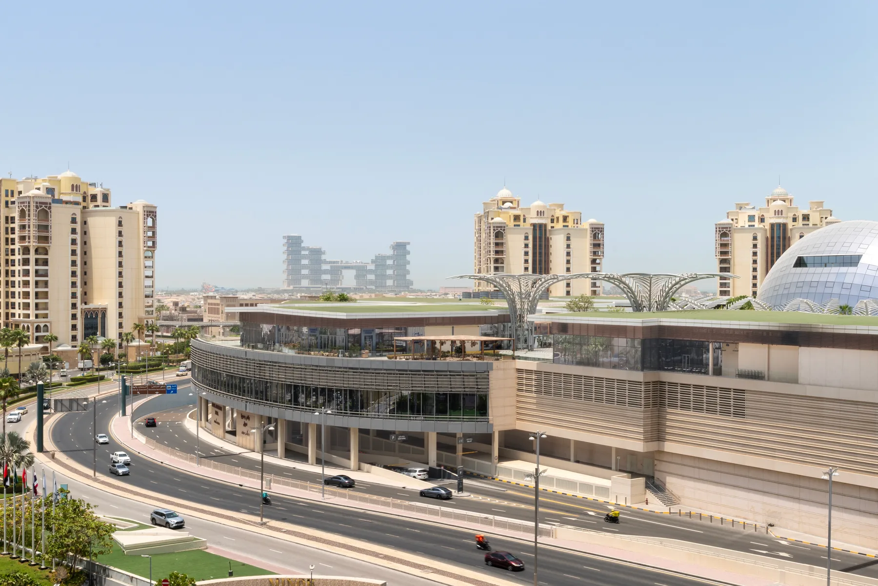 Un complejo comercial moderno con edificios curvos junto a una carretera de varios carriles.