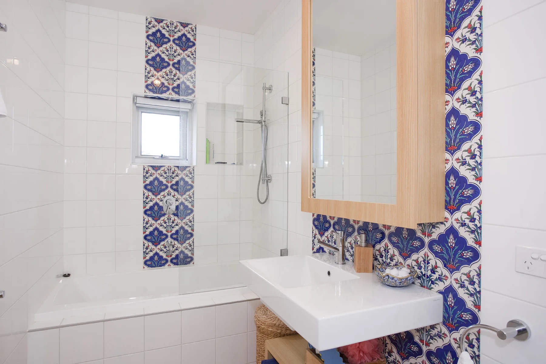 Un baño alicatado con bañera, ducha y lavabo.