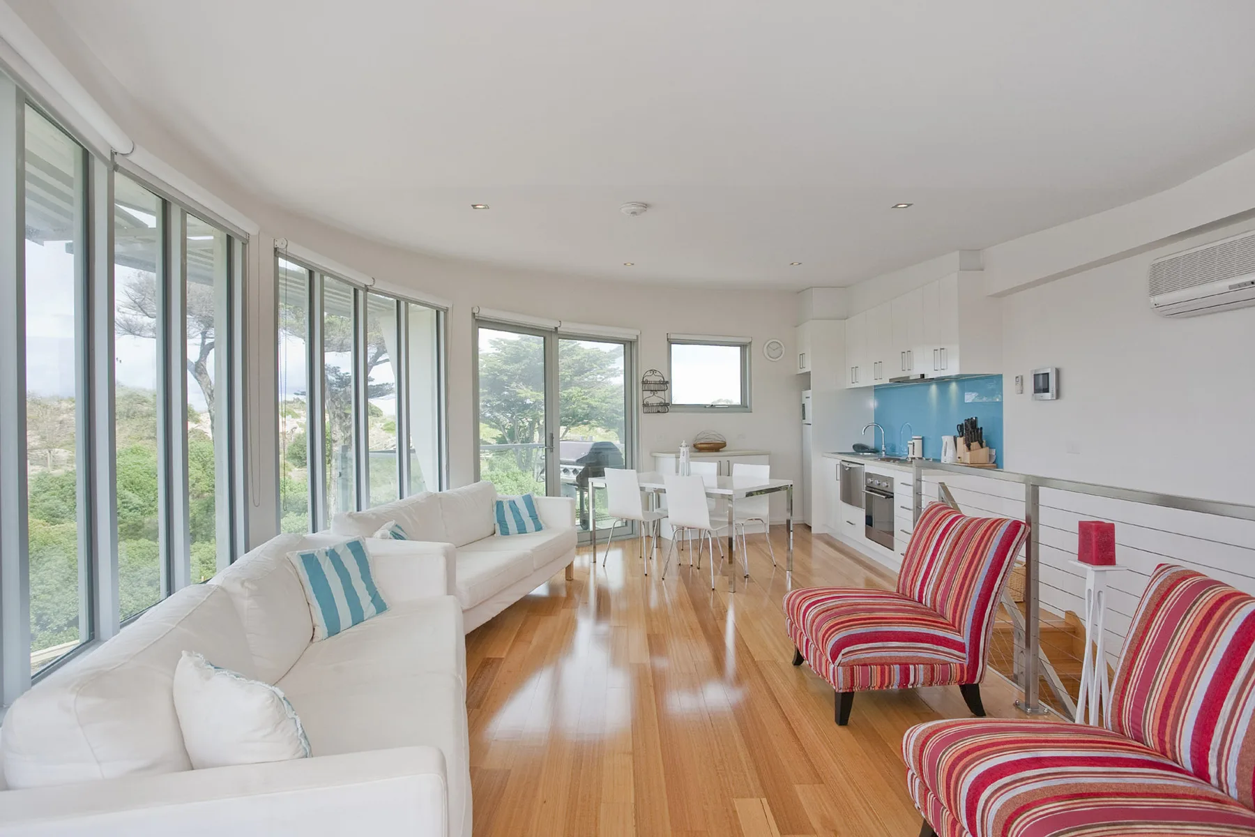 Una luminosa sala de estar con cocina abierta y asientos junto a grandes ventanas.
