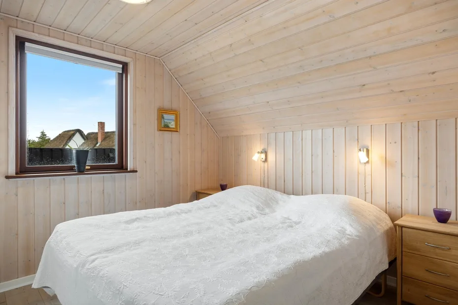 Un dormitorio con una cama cubierta de ropa blanca y una ventana.