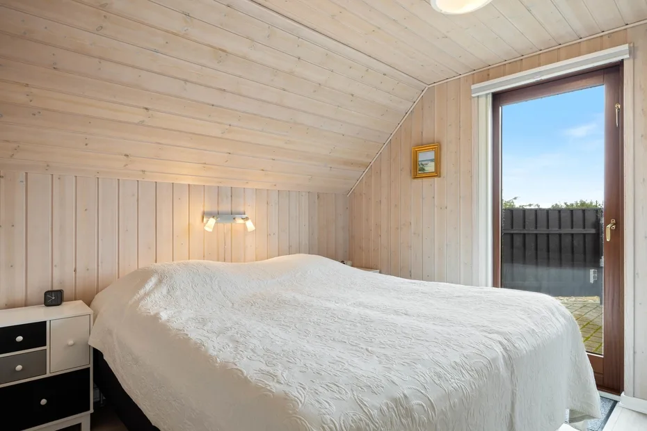 Un dormitorio con una cama grande bajo un techo inclinado revestido de madera.