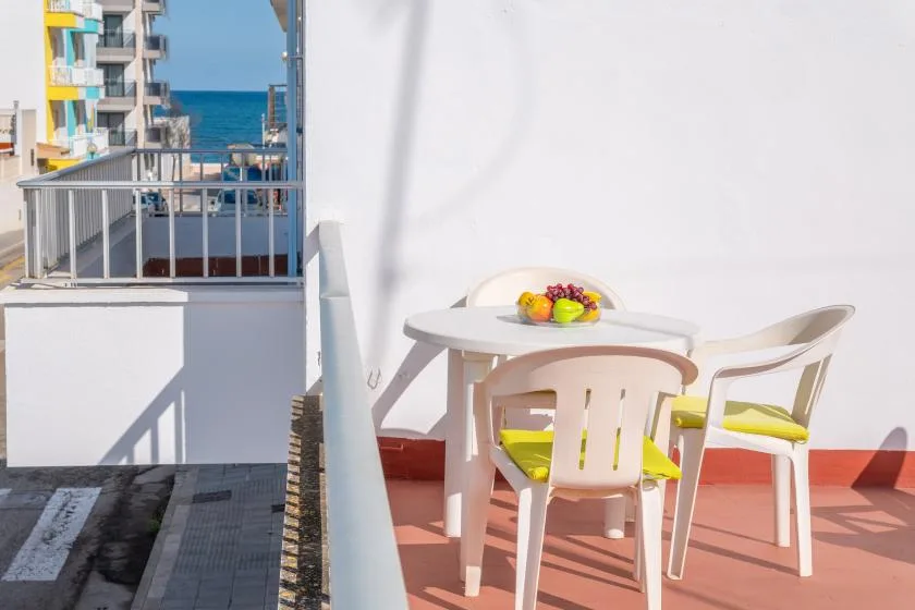 A balcony dining area with a table, seating, and a view of the sea.